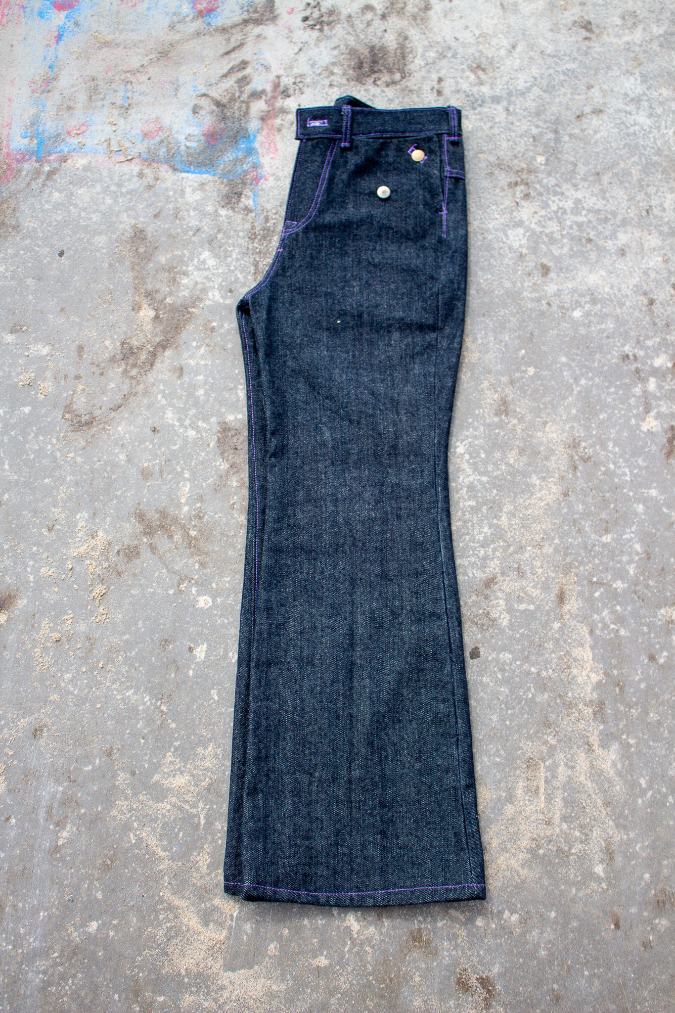 Pair of dark blue jeans on a textured gray surface